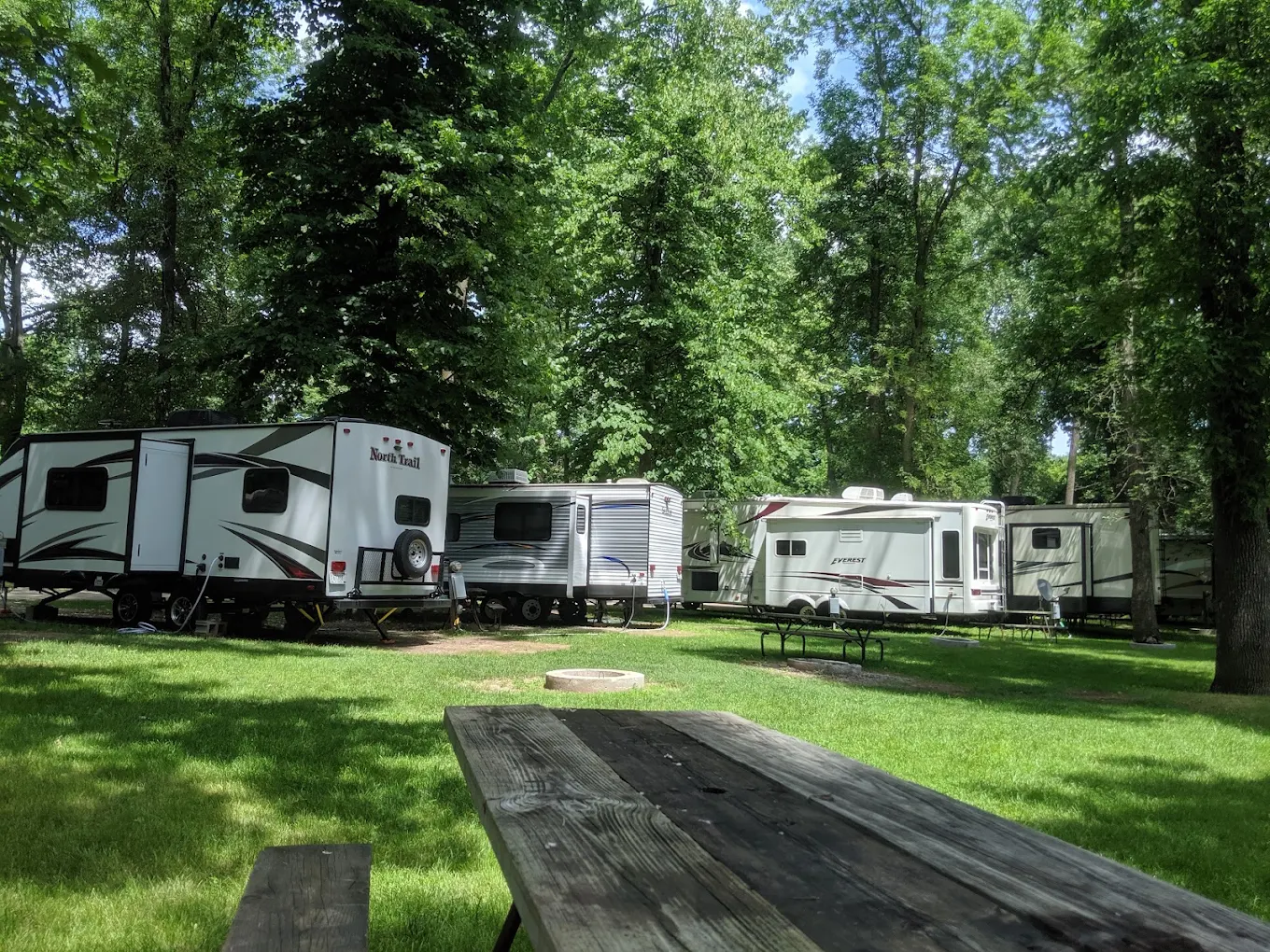 RV campsite surrounded by trees at Apple Creek Campground